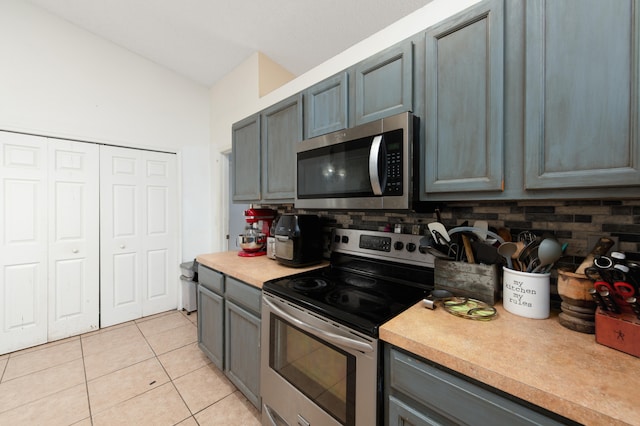 kitchen with backsplash, light tile patterned flooring, and appliances with stainless steel finishes