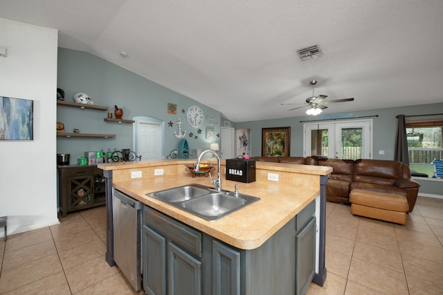 kitchen with light tile patterned flooring, sink, a kitchen island with sink, and vaulted ceiling