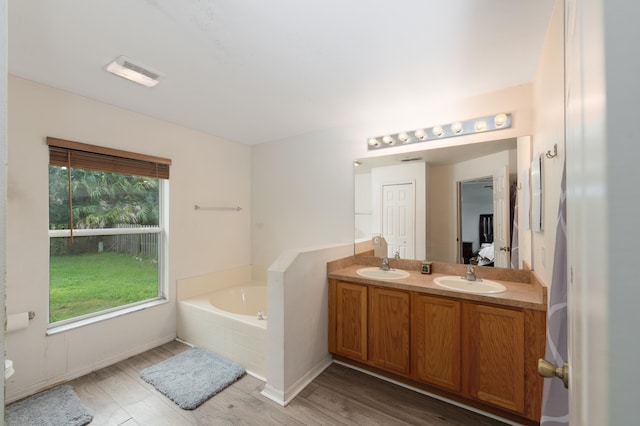 bathroom with vanity, hardwood / wood-style flooring, and a relaxing tiled tub