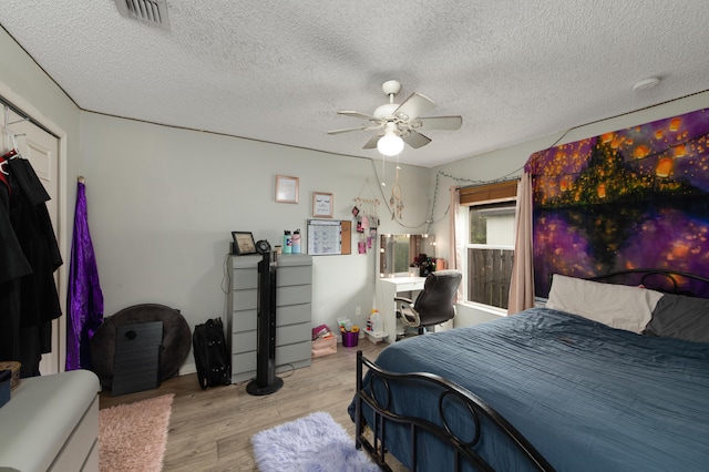 bedroom featuring ceiling fan, light hardwood / wood-style floors, and a textured ceiling