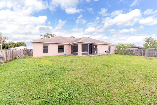 rear view of property with a sunroom, a yard, and central AC unit