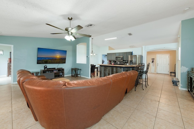 tiled living room featuring ceiling fan, a textured ceiling, and vaulted ceiling