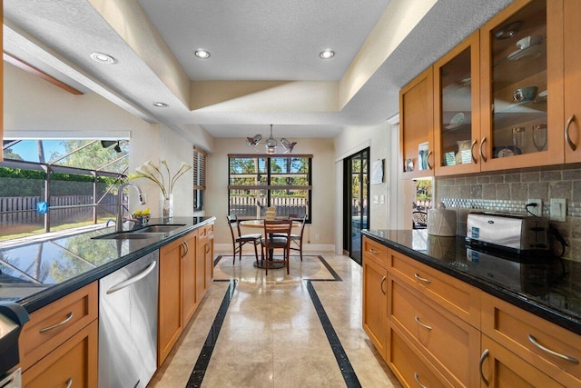 kitchen featuring decorative backsplash, stainless steel dishwasher, a textured ceiling, sink, and a notable chandelier