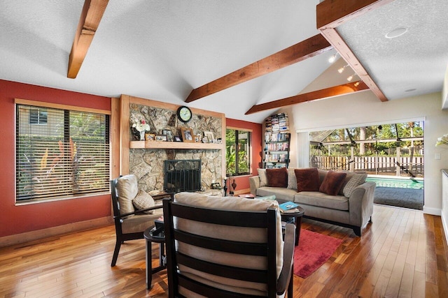 living room featuring hardwood / wood-style floors, lofted ceiling with beams, a fireplace, and a textured ceiling