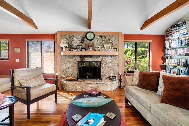 living room with hardwood / wood-style flooring, lofted ceiling with beams, and a fireplace