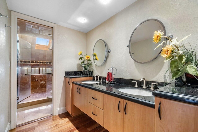 bathroom with hardwood / wood-style floors, vanity, and tiled shower