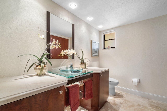 bathroom featuring a textured ceiling, vanity, and toilet