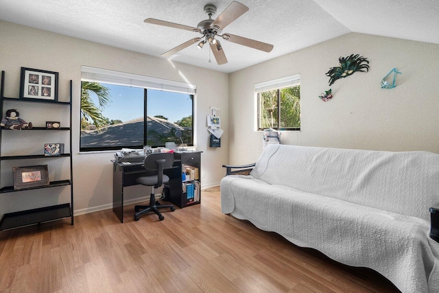 office space featuring a textured ceiling, ceiling fan, light hardwood / wood-style flooring, and lofted ceiling