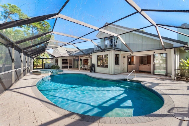 view of pool with an in ground hot tub, a patio, and glass enclosure