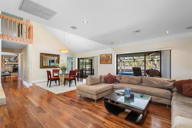 living room with a fireplace, high vaulted ceiling, and hardwood / wood-style flooring