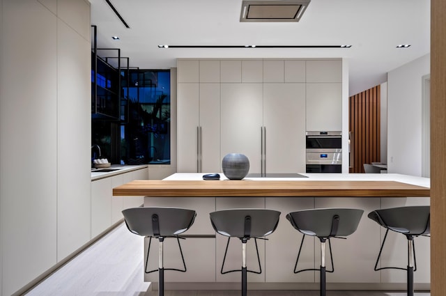 kitchen with white cabinets, a breakfast bar, and double oven