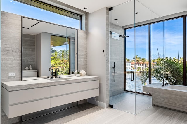 bathroom featuring plus walk in shower, vanity, a water view, and floor to ceiling windows