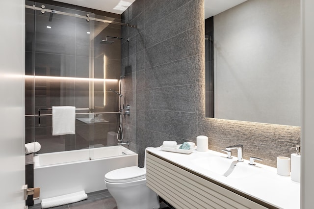 full bathroom featuring backsplash, vanity, shower / bath combination with glass door, tile walls, and toilet