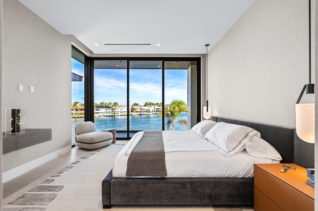 bedroom featuring floor to ceiling windows, a water view, and access to exterior