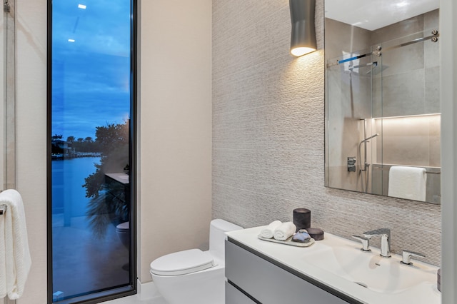 bathroom with walk in shower, vanity, backsplash, toilet, and a water view