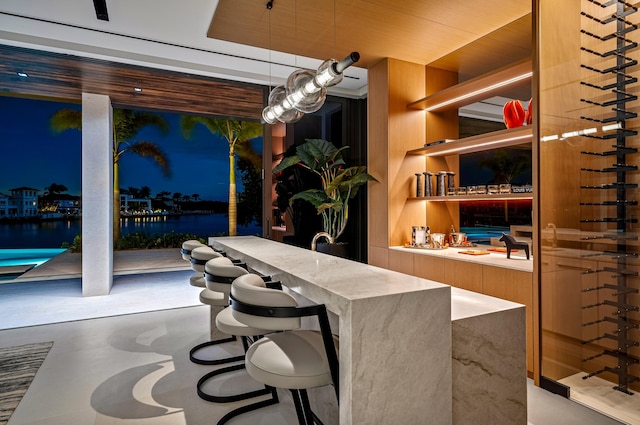 interior space with pendant lighting, a water view, and concrete flooring