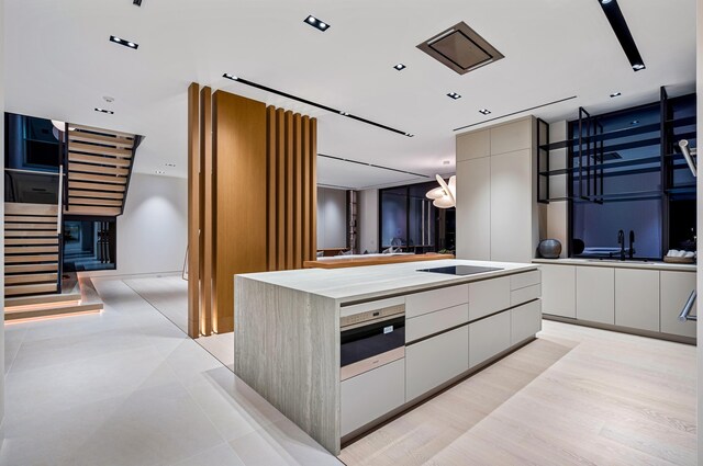 kitchen with sink, a kitchen island, oven, and black electric stovetop