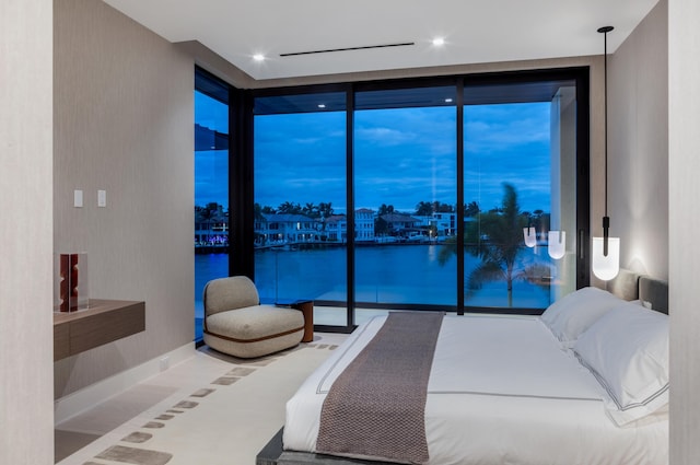 bedroom with floor to ceiling windows and a water view