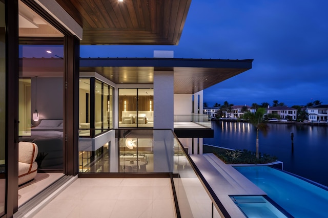 balcony at dusk featuring a water view