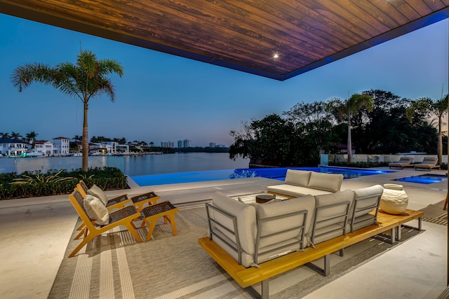 patio terrace at dusk with outdoor lounge area and a water view