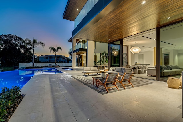 pool at dusk featuring an outdoor living space, an in ground hot tub, and a patio