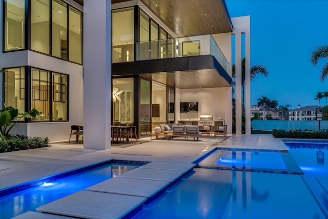 back of house with an outdoor living space, a patio, and a pool with hot tub