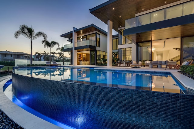 pool at dusk with a patio area and an outdoor hangout area