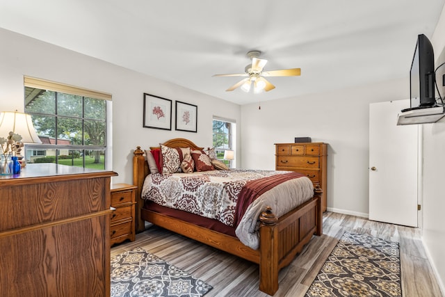 bedroom with multiple windows, ceiling fan, and light hardwood / wood-style floors