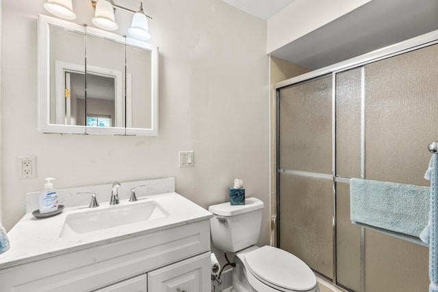 bathroom featuring vanity, an enclosed shower, and toilet