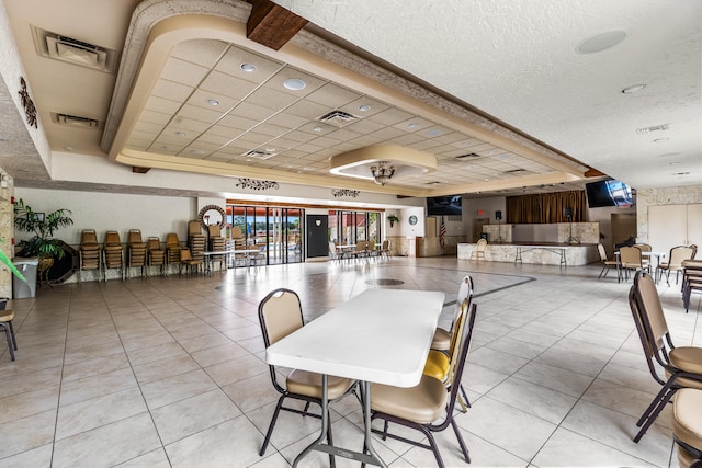 tiled dining space featuring a raised ceiling and a textured ceiling