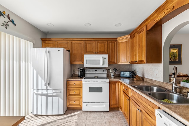 kitchen with decorative backsplash, light tile patterned flooring, white appliances, and sink