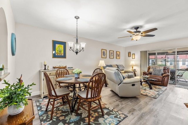 dining area featuring ceiling fan with notable chandelier and light hardwood / wood-style floors