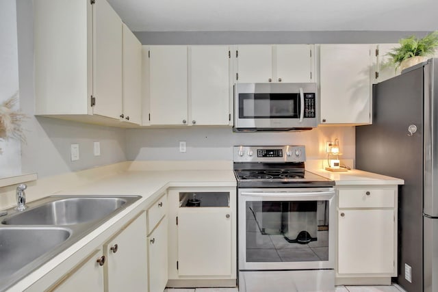 kitchen with white cabinets, light tile patterned floors, appliances with stainless steel finishes, and sink