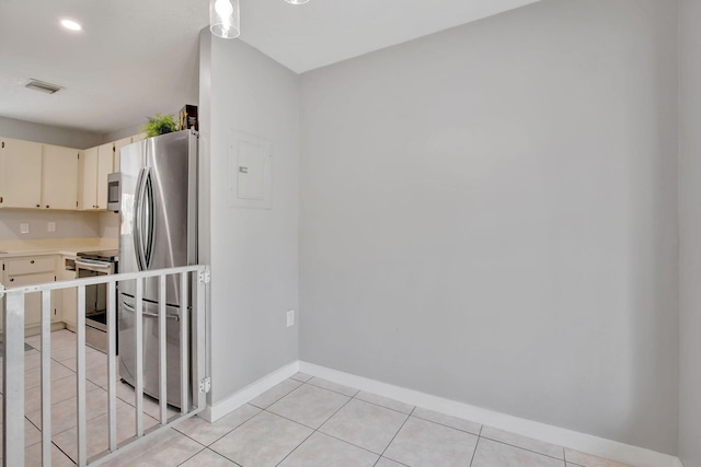 kitchen featuring electric panel, light tile patterned floors, cream cabinets, and appliances with stainless steel finishes