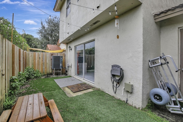 rear view of property with central air condition unit and a yard