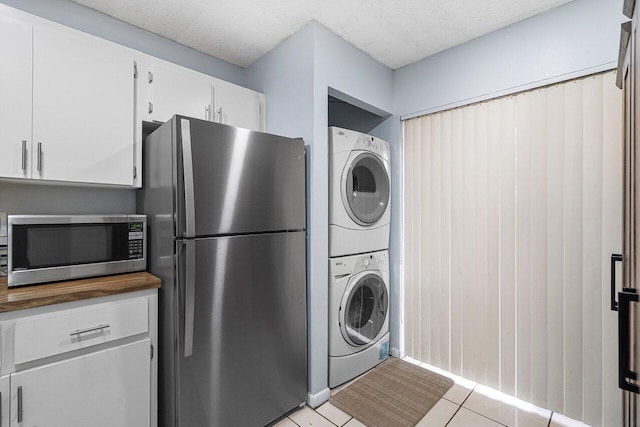 laundry room with stacked washing maching and dryer, a textured ceiling, and light tile patterned flooring