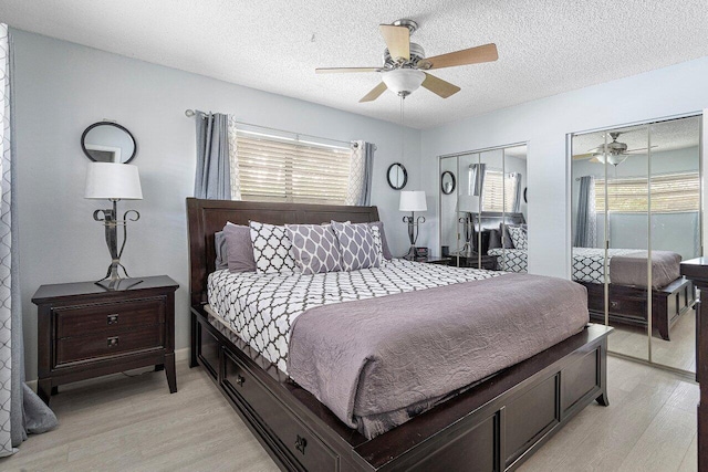 bedroom featuring light wood-type flooring, multiple windows, two closets, and ceiling fan