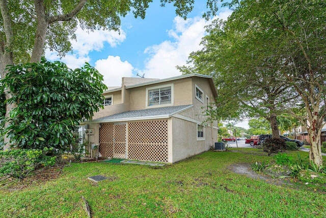 rear view of property with central AC unit and a yard