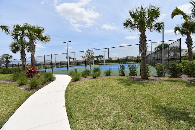 view of home's community with tennis court, a water view, and a yard