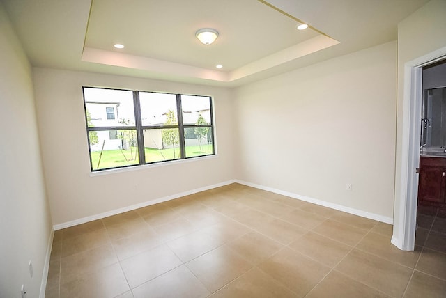 tiled spare room featuring a raised ceiling