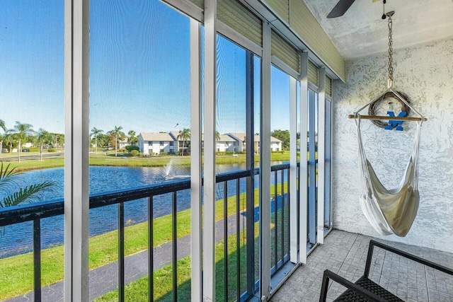 sunroom / solarium with ceiling fan and a water view