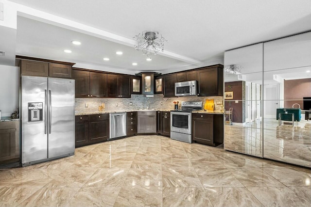 kitchen featuring dark brown cabinetry, stainless steel appliances, light stone counters, and backsplash