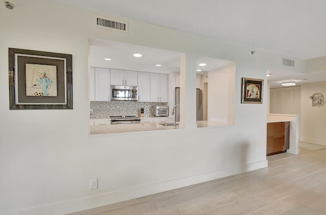 20100 Boca W Dr Unit 125, Boca Raton, FL 33434 - kitchen with stainless steel appliances, white cabinets, a peninsula, baseboards, and recessed lighting