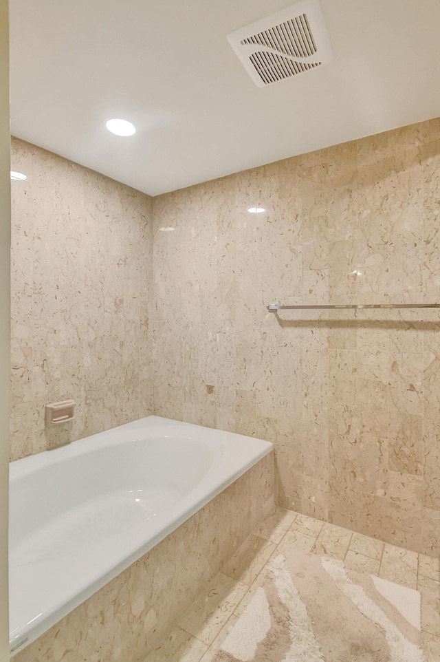 bathroom featuring a relaxing tiled tub and tile walls