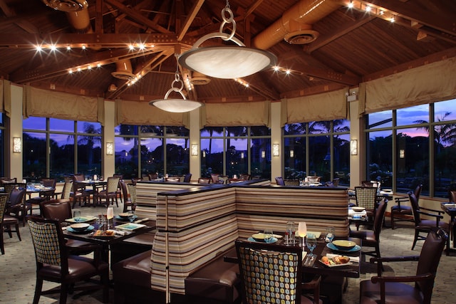 dining space with carpet floors, beamed ceiling, high vaulted ceiling, and wooden ceiling