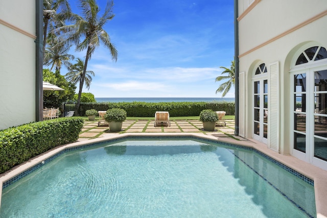 view of swimming pool with a water view and a patio area