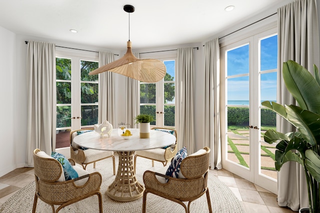 dining room featuring a water view, french doors, and light tile patterned floors