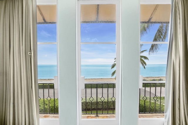 doorway to outside with a water view, a view of the beach, and a healthy amount of sunlight