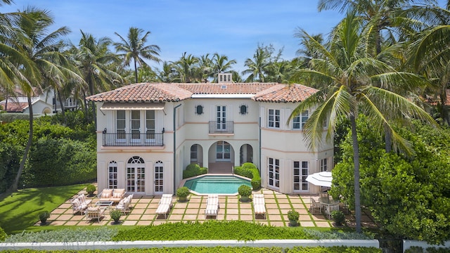 rear view of house with a patio area, french doors, and a balcony