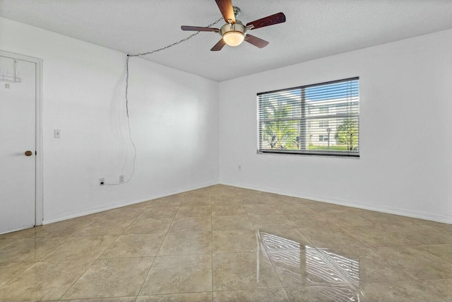 empty room featuring ceiling fan, light tile patterned floors, and a textured ceiling